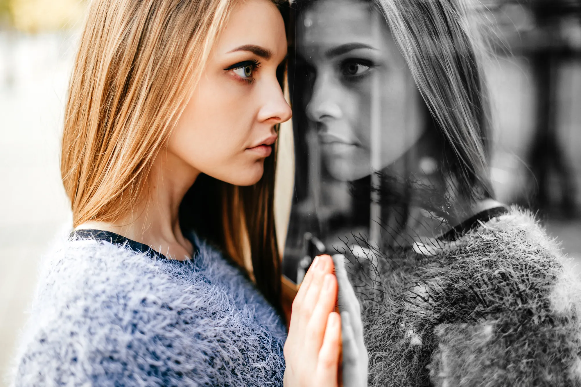 A woman's reflection in a window, half in color and half in monochrome